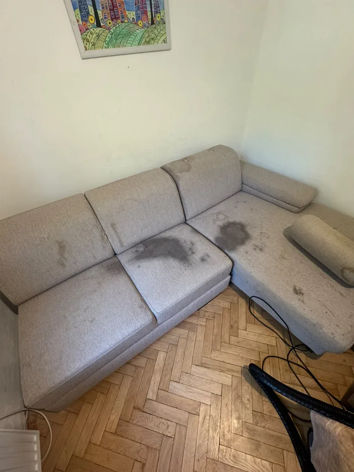 Grey corner sofa with dark stains across the seats before cleaning, Budapest flat